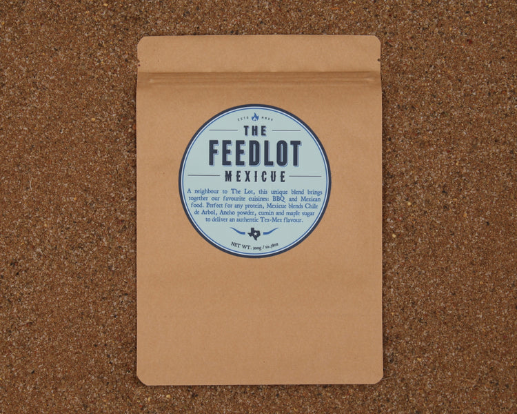 A brown paper package with a circular label that reads "The Feedlot Mexicue." The package is set against a textured, brown background. The label mentions that it contains a unique blend of spices for BBQ and Mexican cuisine, offering an authentic Tex-Mex flavor, weighing 75g.